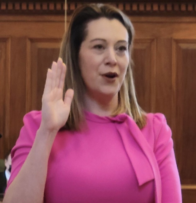 A woman in pink is holding up her hand.