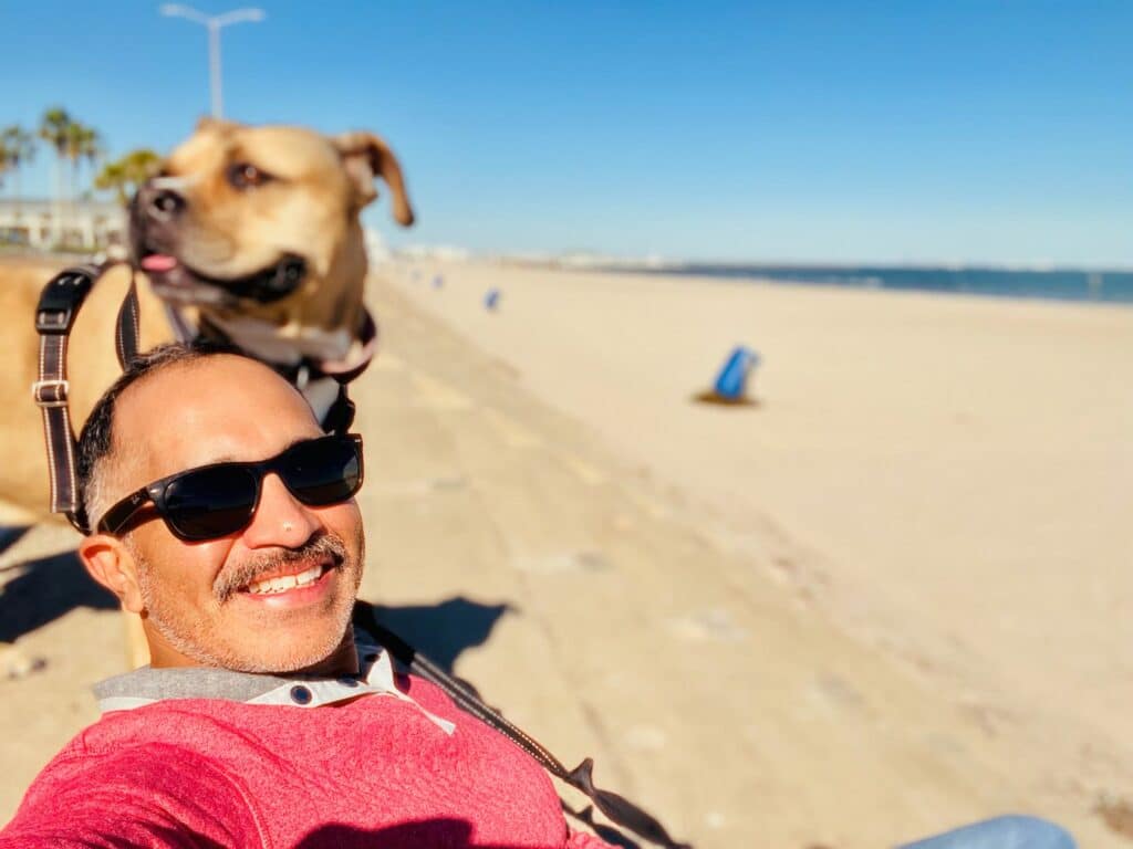 A man and his dog are sitting on the beach.