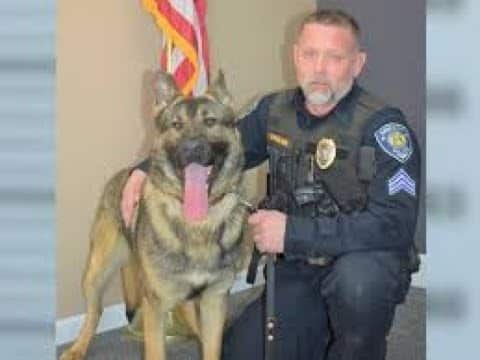 A police officer and his dog pose for the camera.