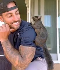 A man holding a small animal on his shoulder.