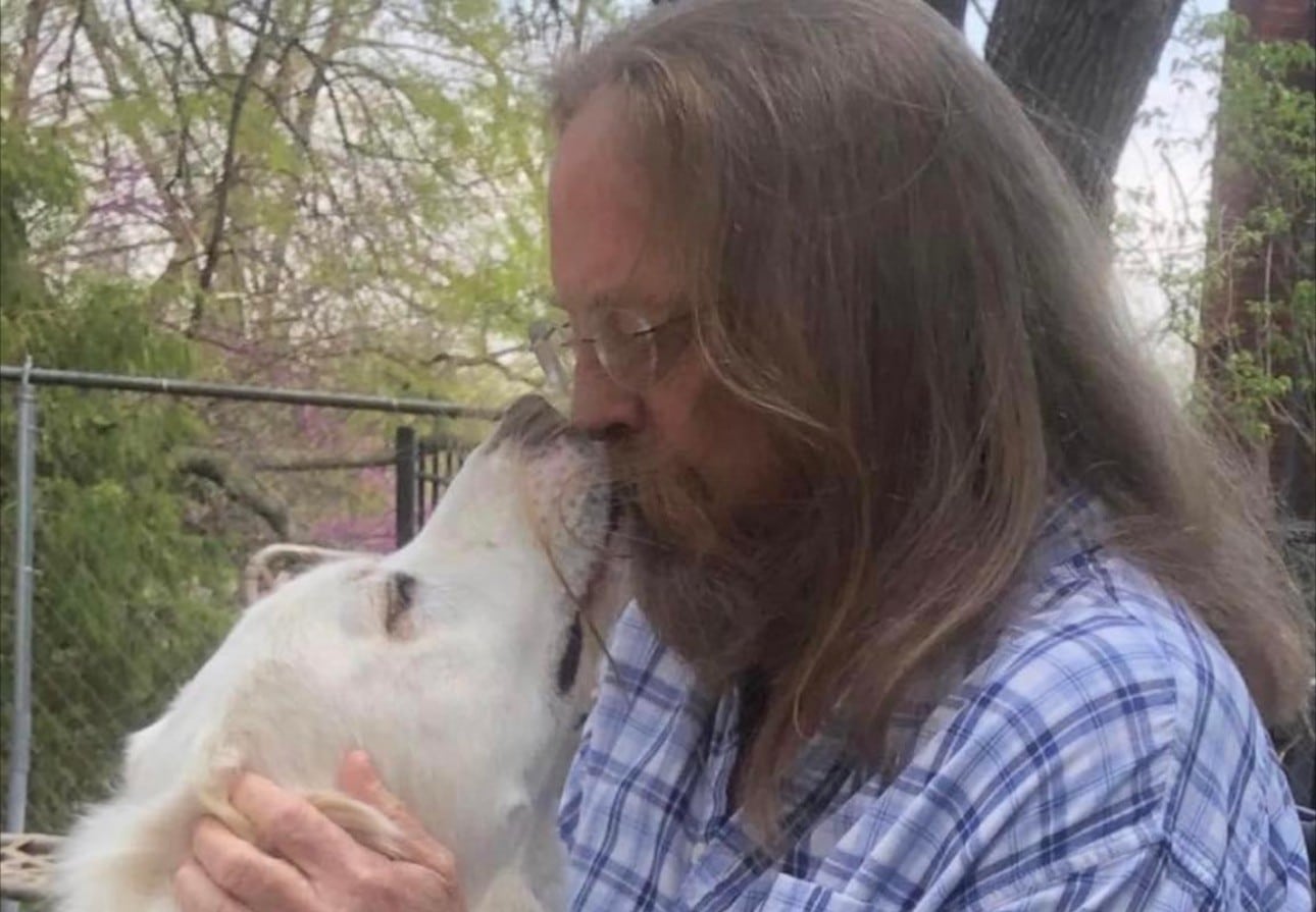 A man kissing a bird on the nose.