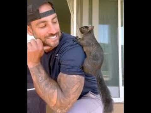 A man holding a small animal on his chest.