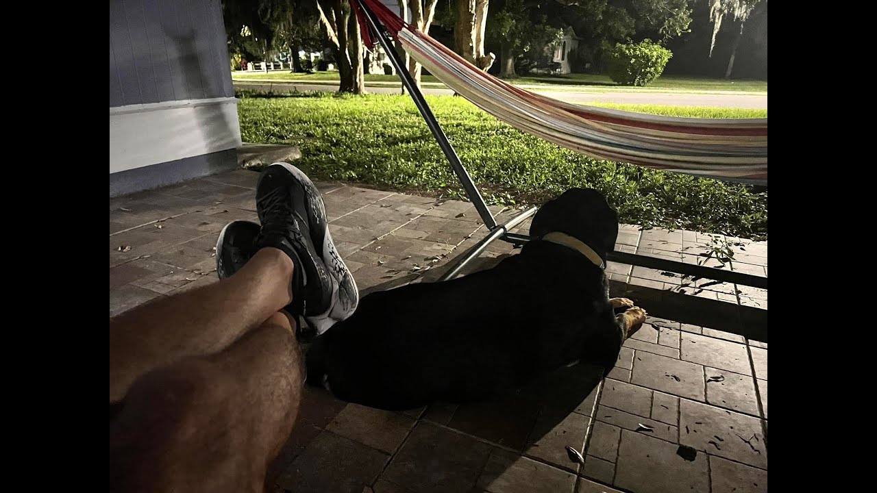 A person 's feet and dog laying on the ground.