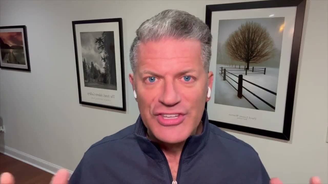 A man with gray hair and wearing ear buds.
