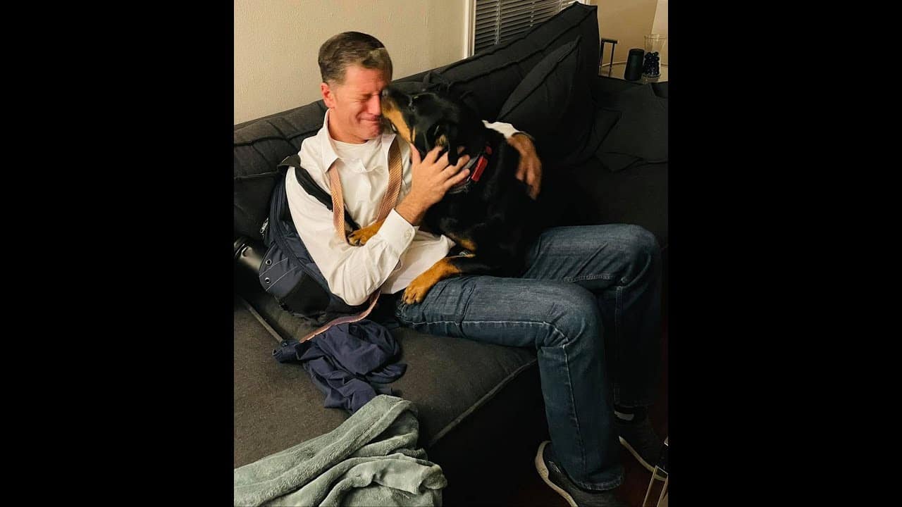 A man sitting on the couch with his dog.