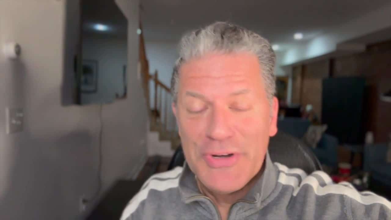 A man with grey hair is looking at the camera.