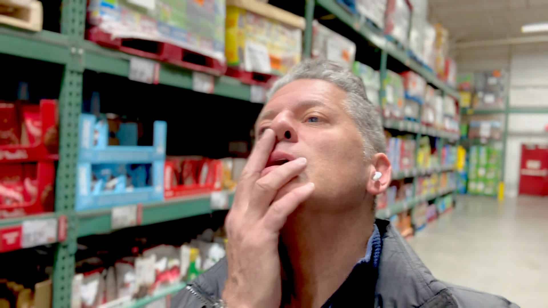 A man is smoking in front of shelves.