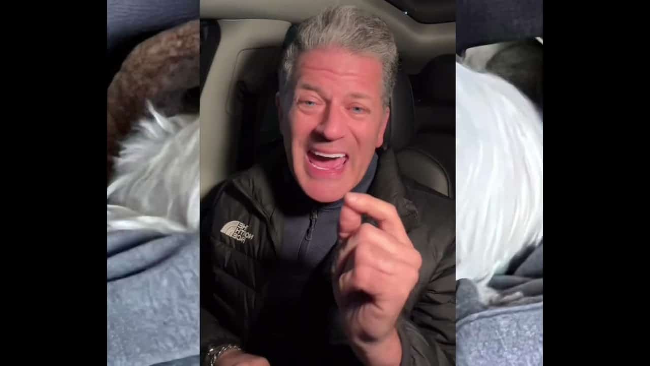 A man is laughing while sitting in his car.