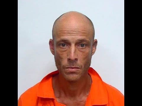 A man in an orange shirt is posing for the camera.