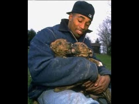 A man holding two puppies in his arms.