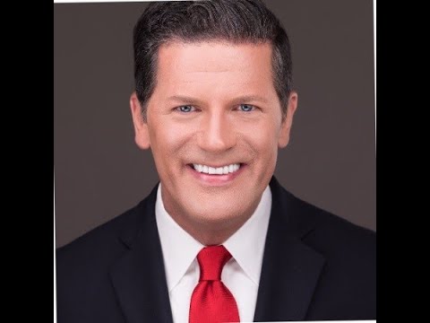 A man in a suit and tie smiling for the camera.
