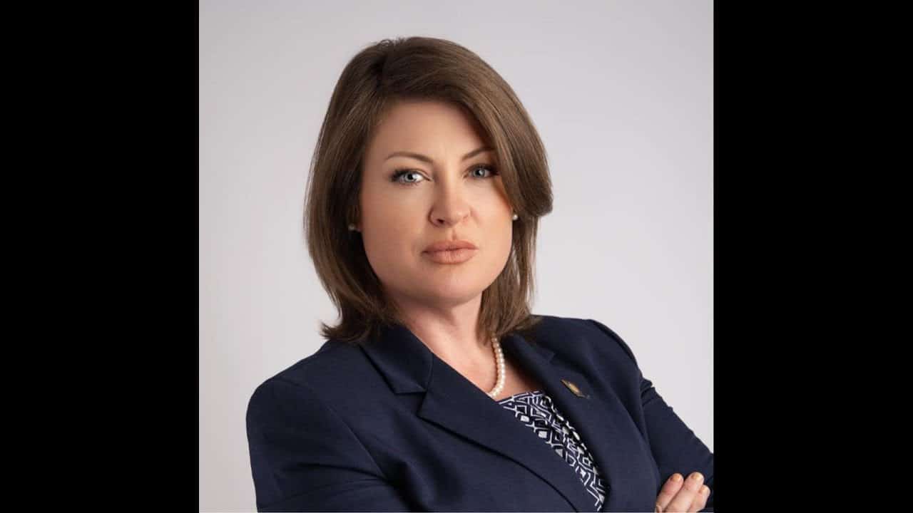 A woman with brown hair and wearing a blue jacket.